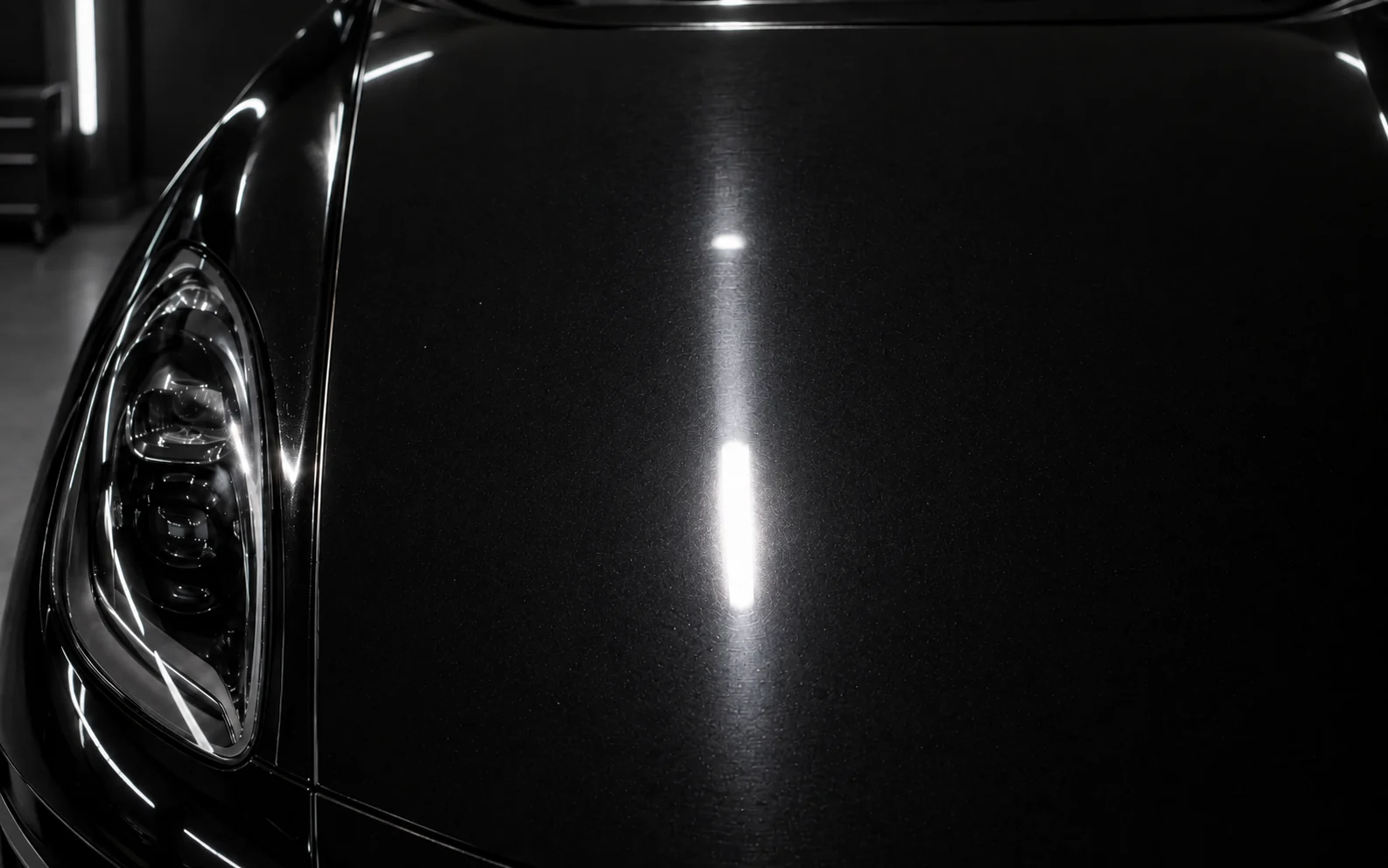The same black Porsche Macan paint after correction, showing improved clarity under the same inspection light